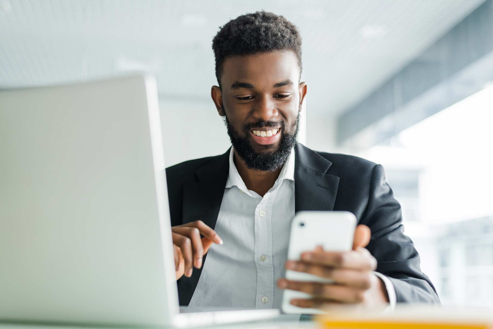 Man sitting in front of his laptop smiling at his phone