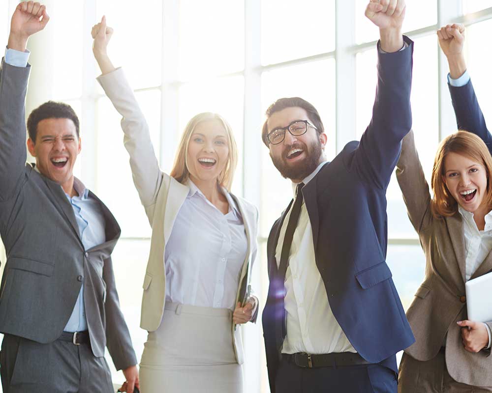 Four happy people with fists in the air